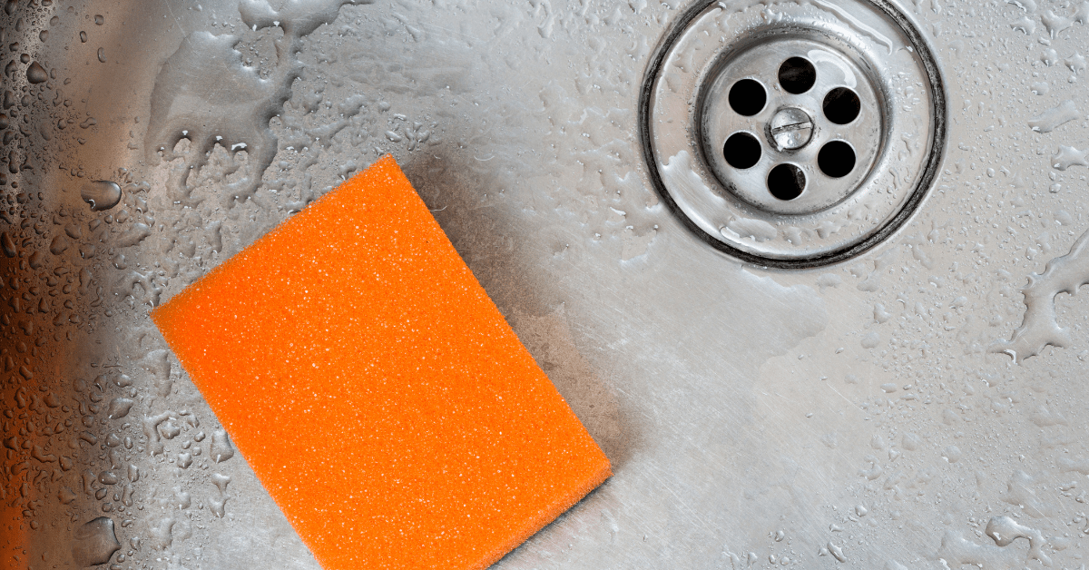 Orange sponge in a stainless steel sink.