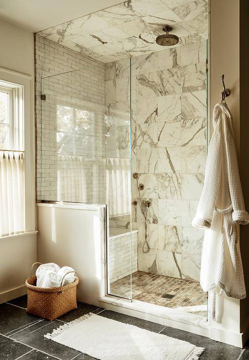 Marble grid walk in shower features gray marble offset floor tiles, a marble slab shower bench and clear shower partition.