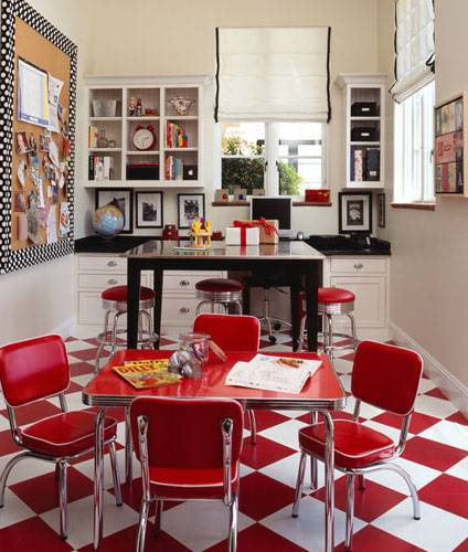 Fun craft room with white & red checkered floors, red retro mini table with red vinyl retro mini chairs, pub table, retro red bar stools, built-in cabinets & cubbies with black granite countertops and white roman shade with black ribbon trim.