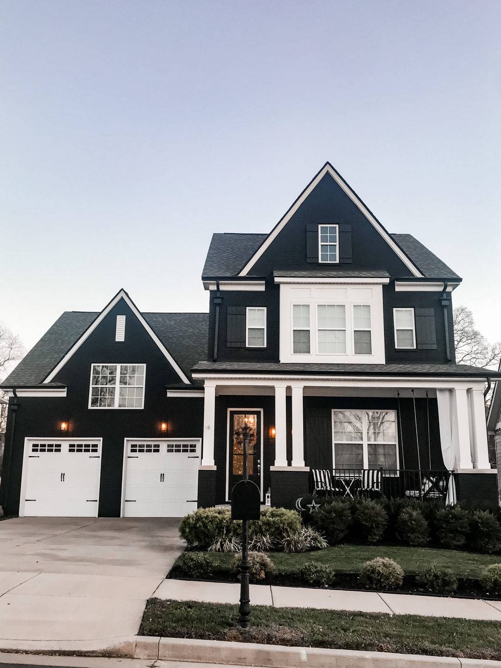 Large black brick house with two white garage doors.
