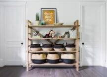 Boys nursery designed with a wooden shelving unit and dip dyed baskets for storage. Gray wood floors keep a neutral surface along with white walls in a nice, light, and airy nursery space.