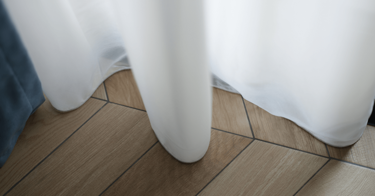 A white curtain with perfect length almost touching floor.