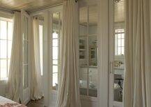 Stunning en suite bathroom design features wall of glass doors covered in floor to ceiling ivory grommet drapes.