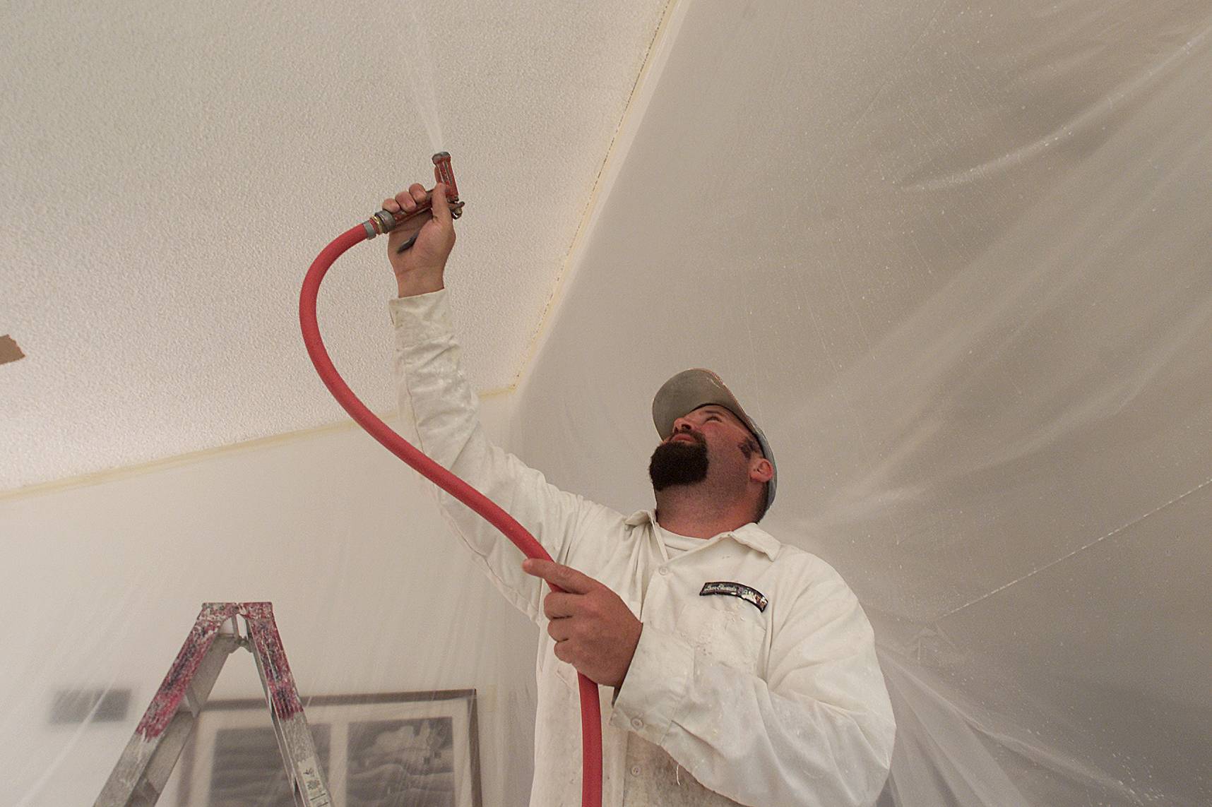 Scott Bickford sprays water over Acoustic ceilings before the scraping begins inside a Thousand Oaks