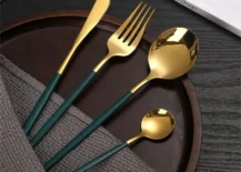 gold and green silverware on wood dish with dish cloth