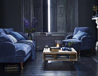 dark elegant living room with indigo blue velvet couches and low coffee table covered in candles and books