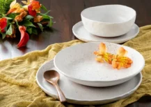 stoneware white dishes on mustard color cheesecloth with flowers on top