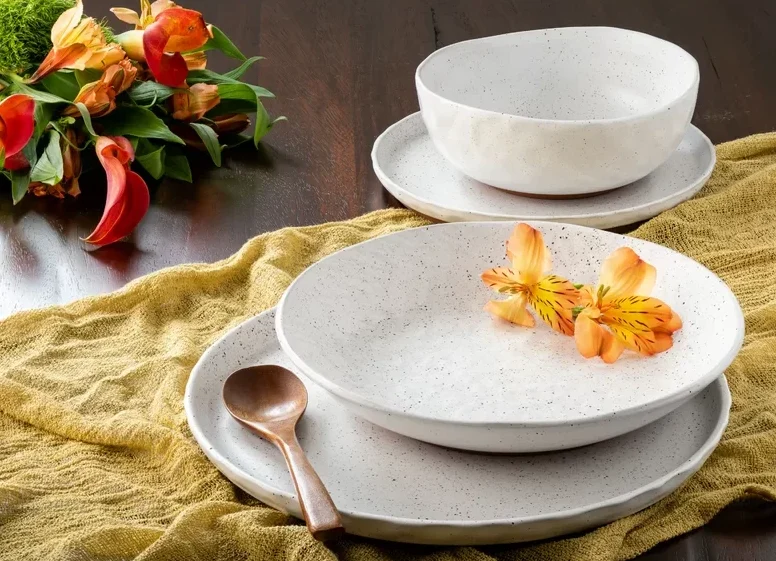 stoneware white dishes on mustard color cheesecloth with flowers on top