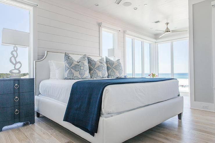 White and blue cottage bedroom features Bungalow 5 Bardot 3 Drawer Dressers placed flanking a white French bed dressed in white and blue bedding complemented with white and blue pillows. The bed sits against a white shiplap wall between windows.