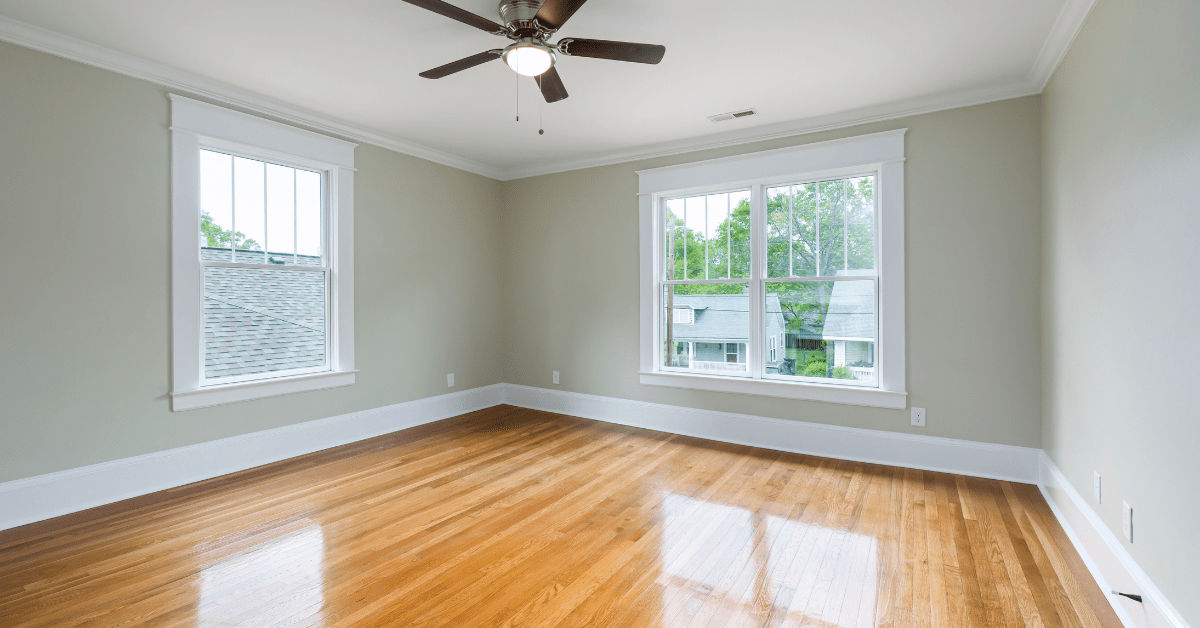 A room with polished wood floors, white ceiling, and beige walls.