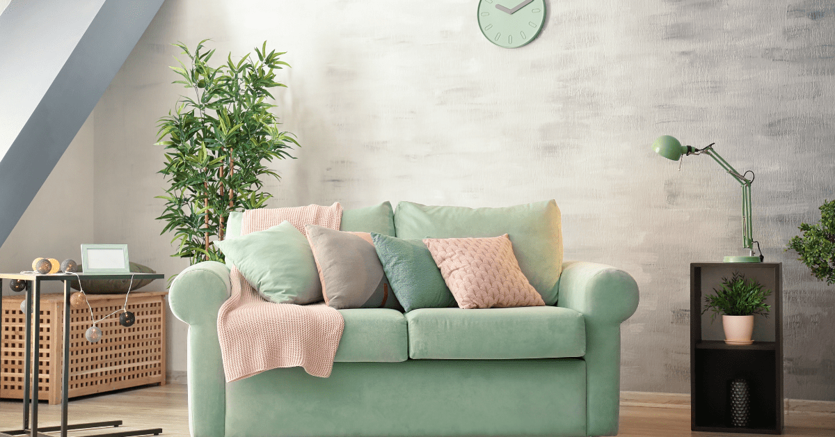 Soft mint couch with pink throw pillows.