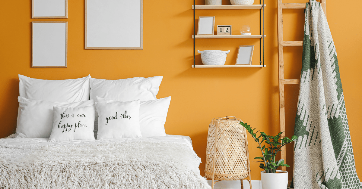 A bedroom with orange wall with white bedding.