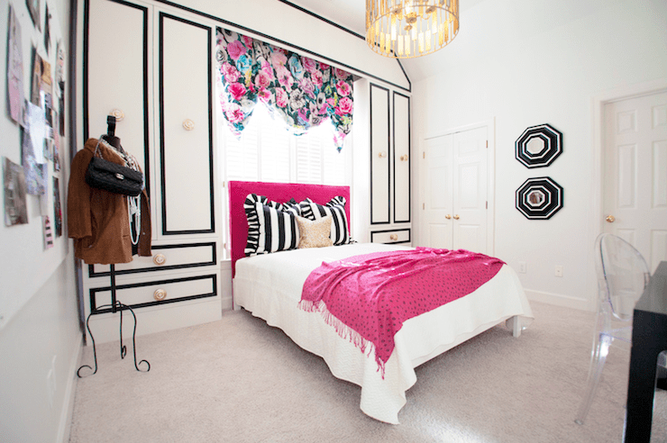 Glamorous teenage girls bedroom with black, white and pink color scheme. Teen girl's bedroom with white and black cabinets and white and black cornice box framing hot pink headboard. Hot Pink velvet headboard with white and black awning stripe ruffled pillows. White cabinets with black trim and brass hardware flanking bed and floral valance over bed. Bed in front of window covered in floral valance layered over plantation shutters. Worlds Away Chrialto Pendant Chandelier over bed.Teen girl's bed with white coverlet, black and white striped ruffled pillows, gold accent pillow and pink fringed throw at foot of bed. White walls with bold black and white octagonal mirrors between doorways. Worlds Away ChRialto Chandelier Pendant hangs over bed.