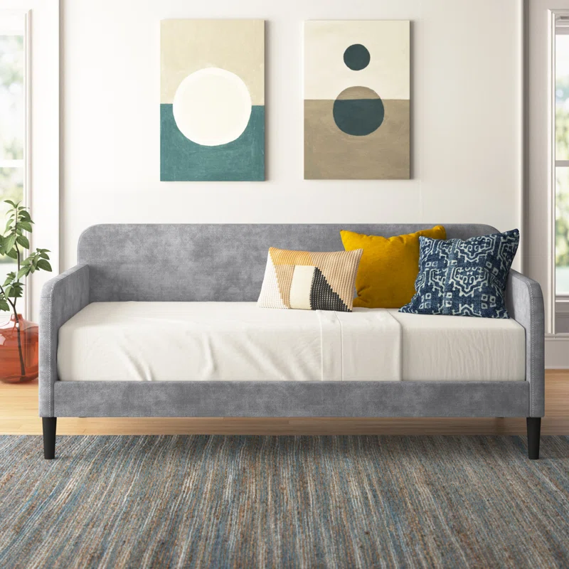Upholstered day bed grey with mustard pillow blue modern art hanging in background