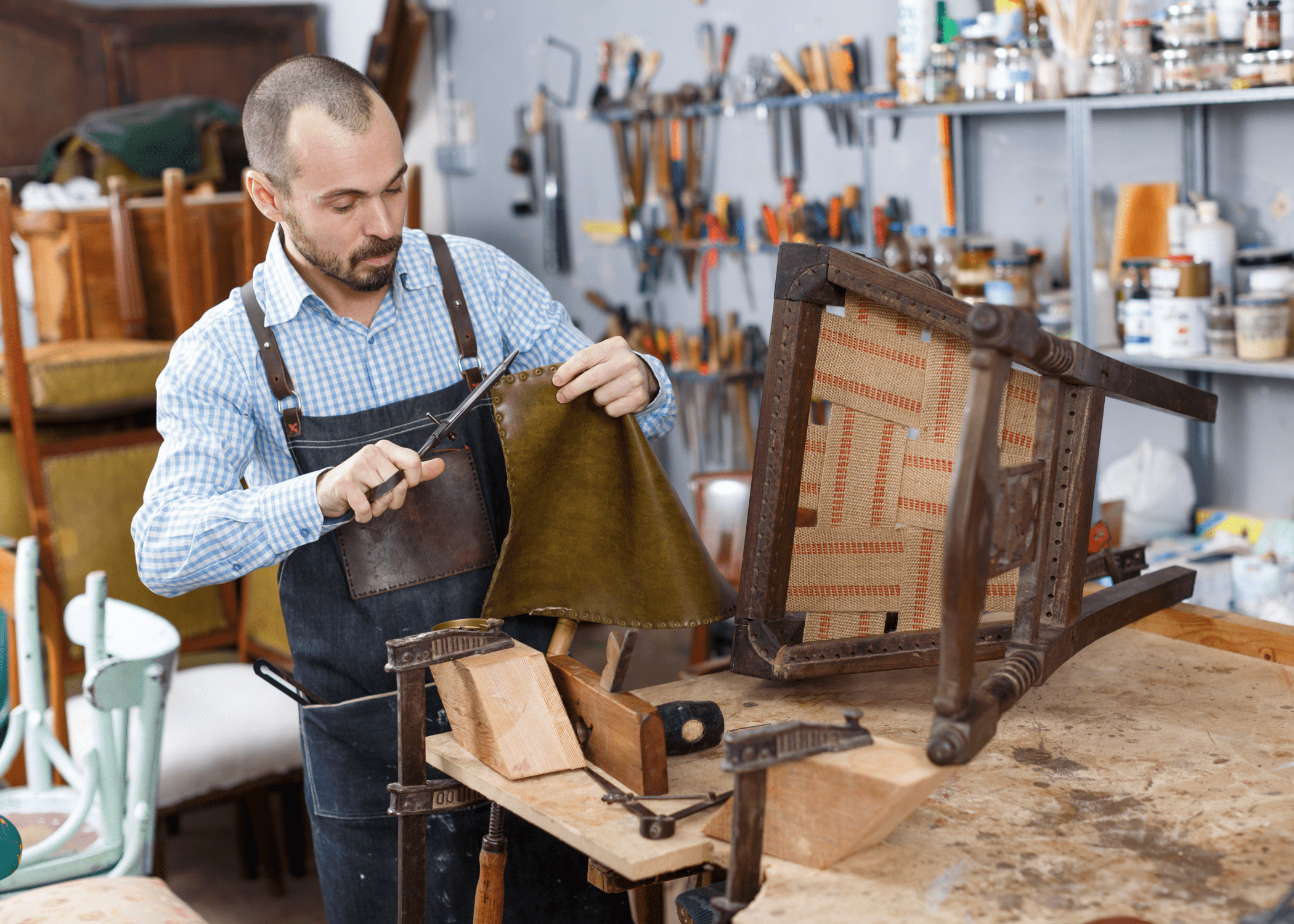 man working on reupholstering a wood chair with leather