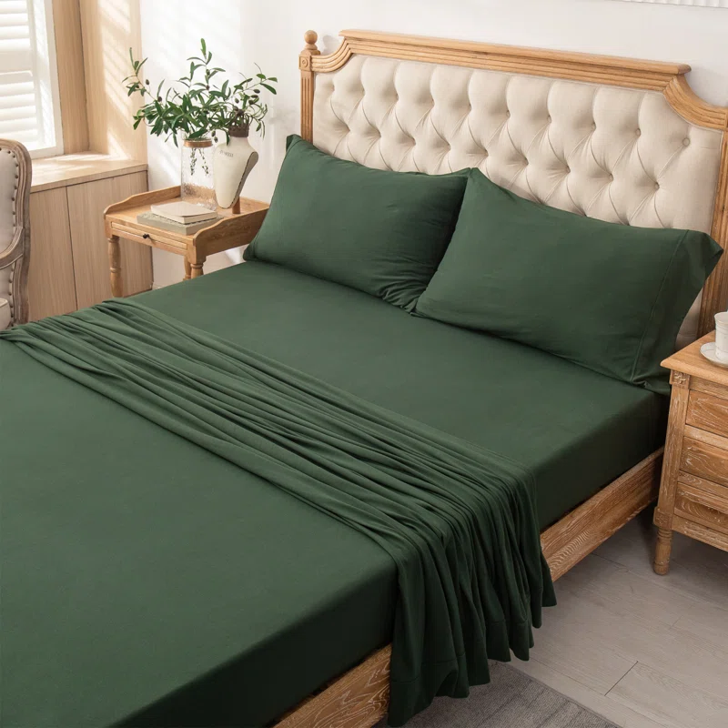green sheet set on queen bed with tufted headboard