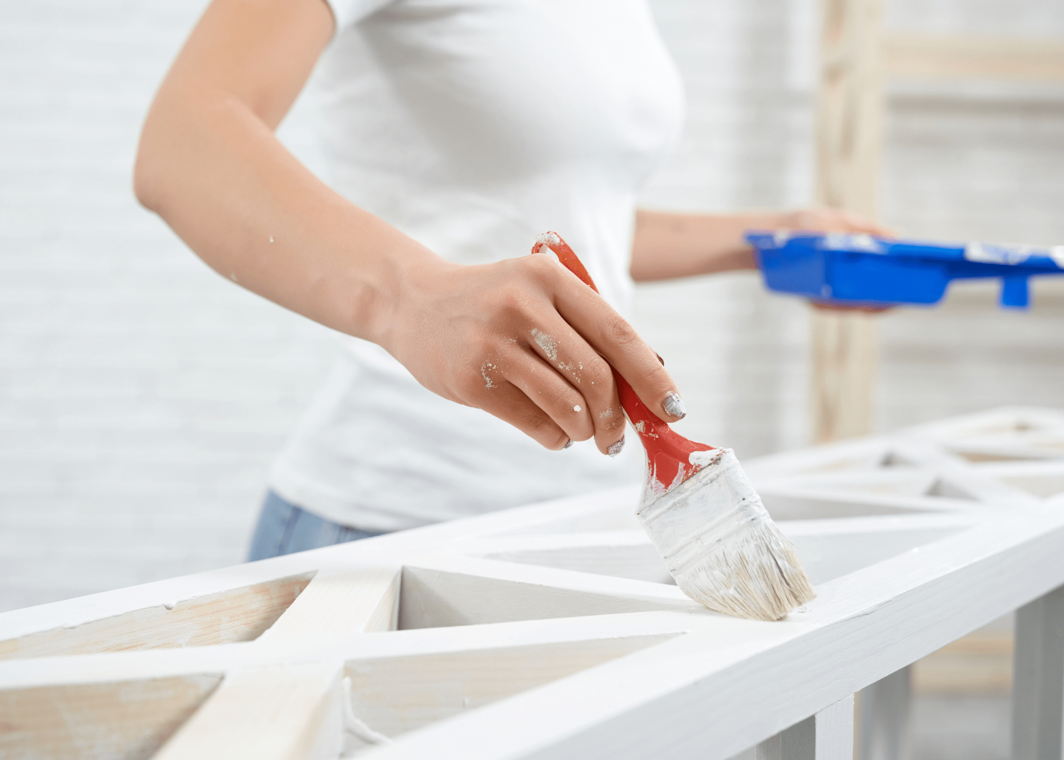 woman painting white piece of furniture