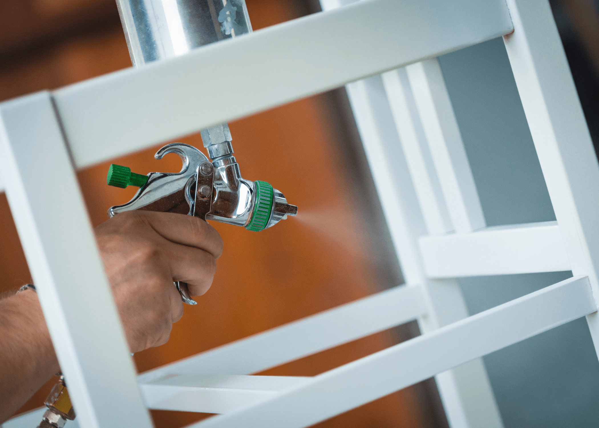close up of someone spraying a piece of furniture with an airbrushing paint sprayer