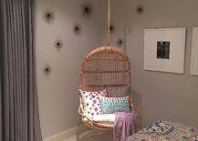 Chic girl's bedroom features a corner hanging chair, Two's Company Hanging Rattan Chair, flanked by sea urchins to the left and a black and white photo gallery to the right.