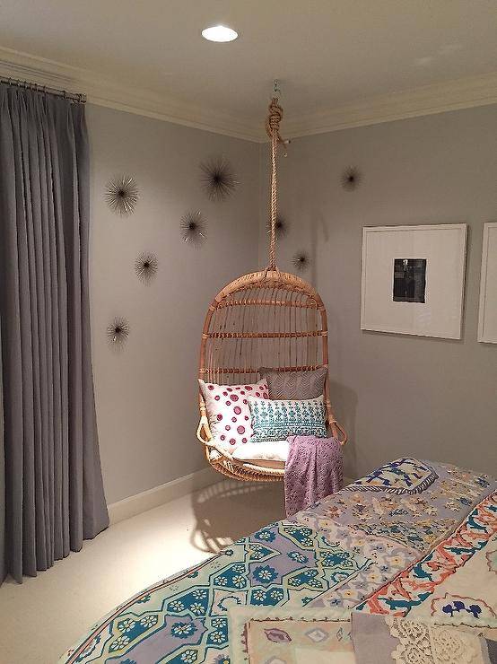 Chic girl's bedroom features a corner hanging chair, Two's Company Hanging Rattan Chair, flanked by sea urchins to the left and a black and white photo gallery to the right.