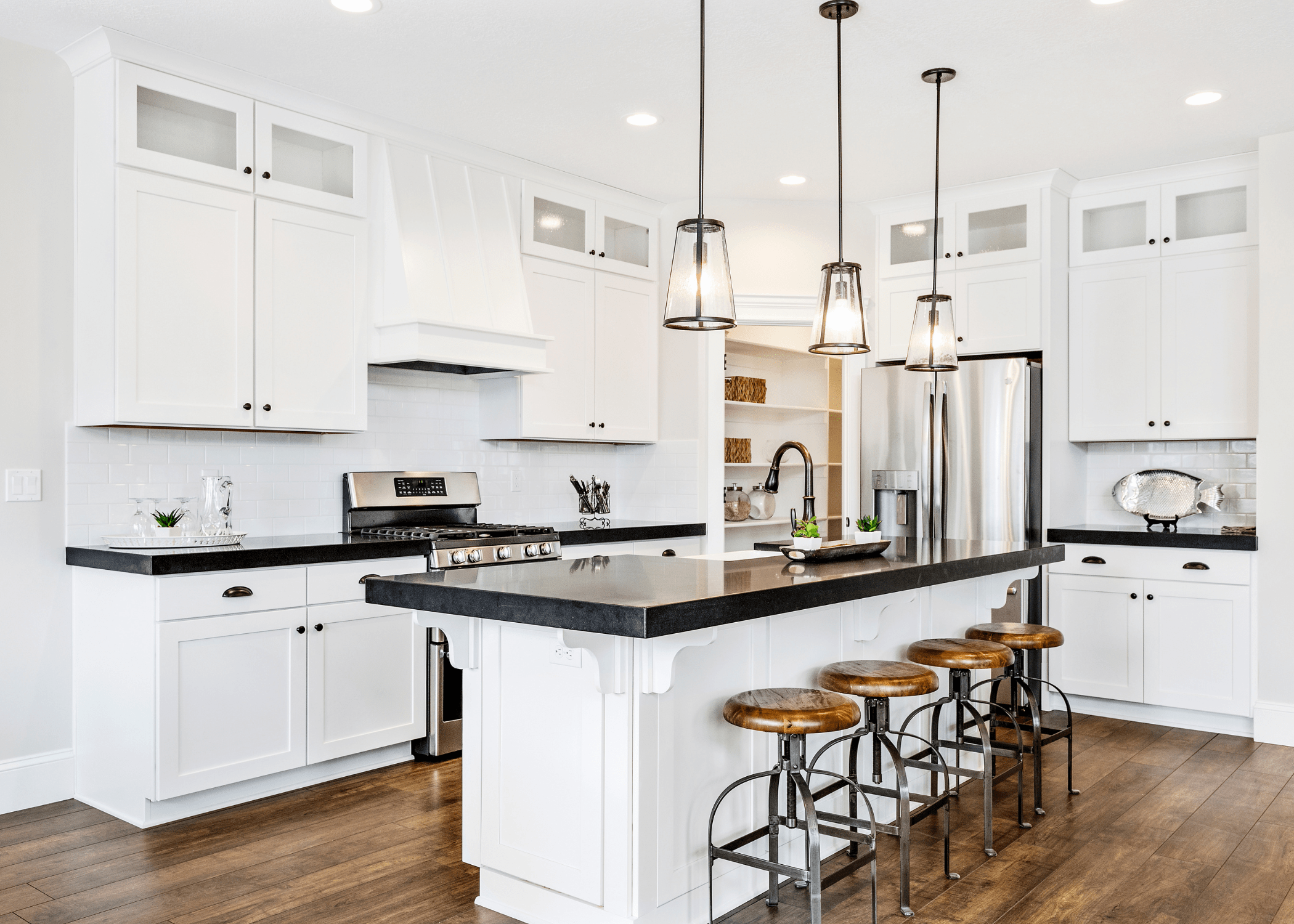 black and white kitchen with hanging pendants center island and wood bar stools