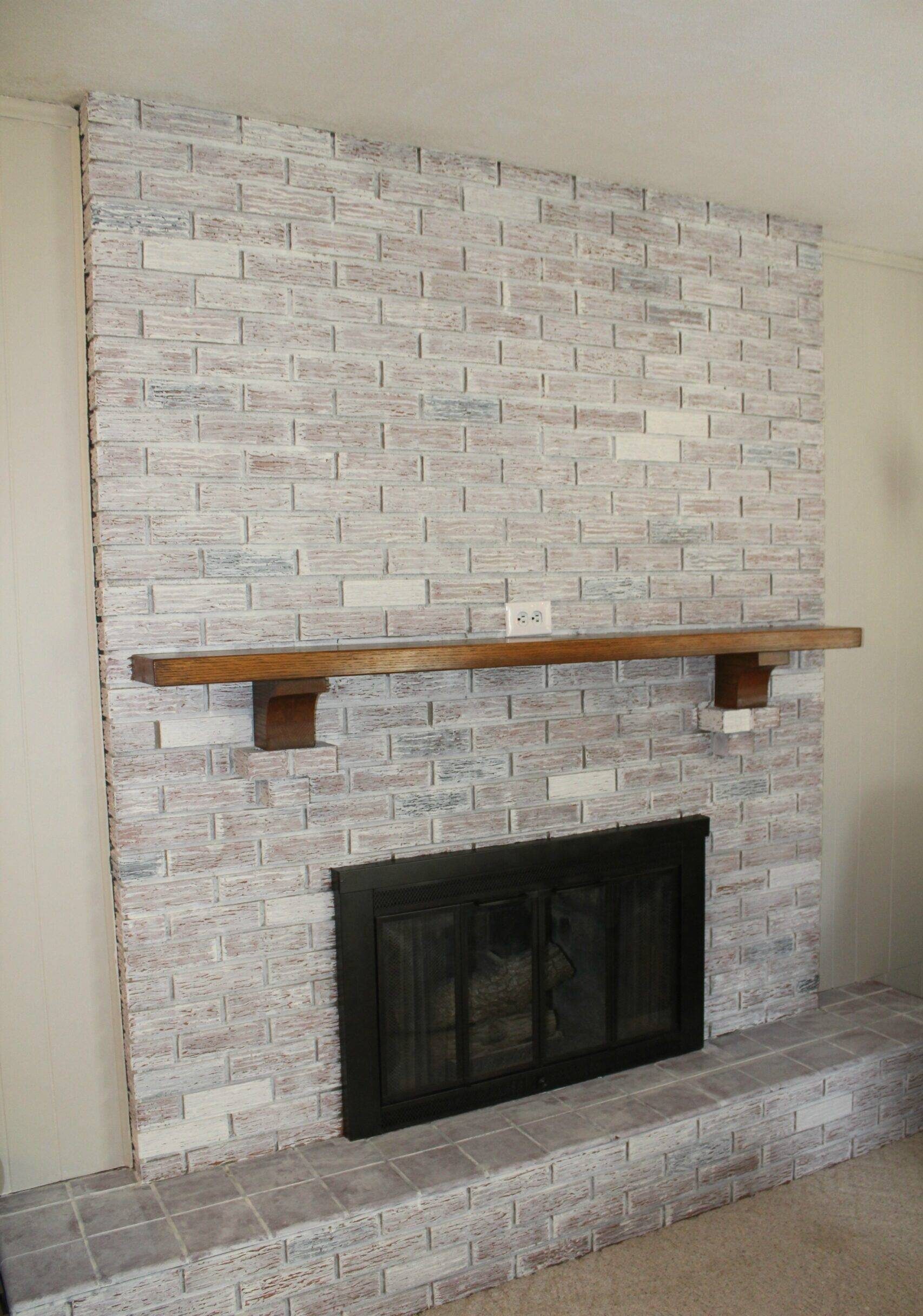 A whitewash fireplace with wooden floating shelve above it.