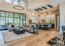 A large open concept living room with rug, chandelier, and light wooden floors.