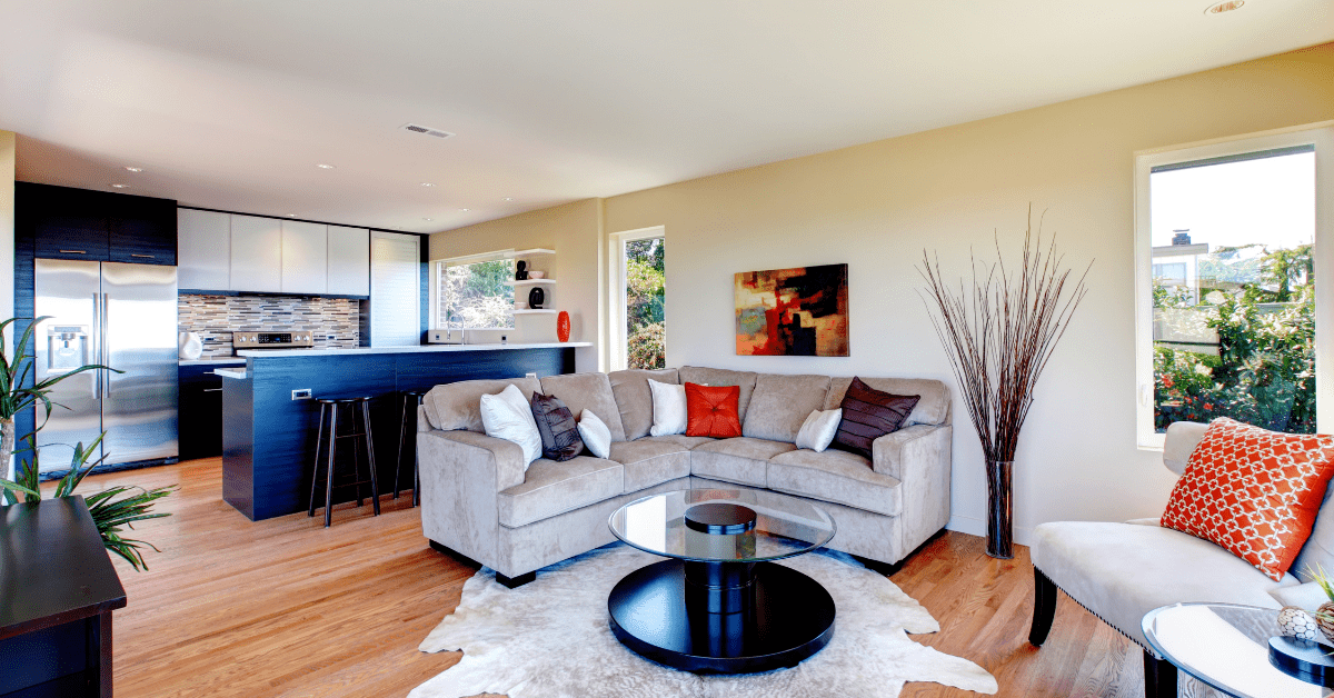 An open concept living room with grey couch and colorful throw pillows.