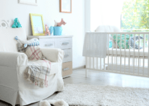 A white nursery with small dresser and a chair.