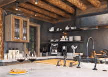 A rustic kitchen with black walls and wood beam ceiling.