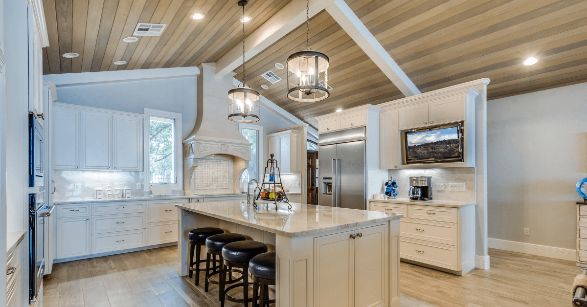A modern white kitchen with light wood ceiling.