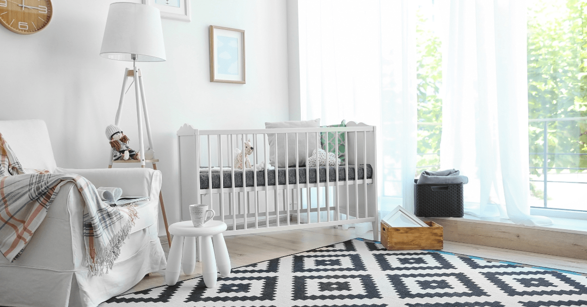 White small nursery room with black and white rug.