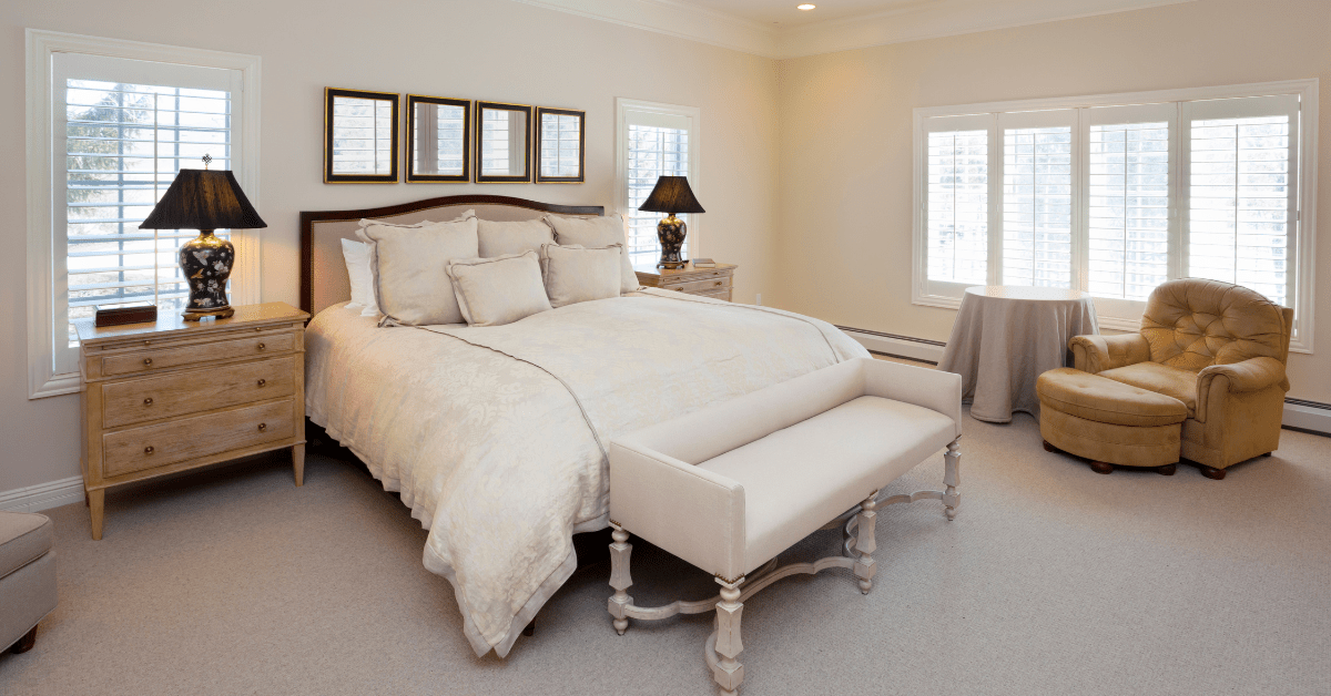 Large white bed in a master bedroom with pictures hung overhead.