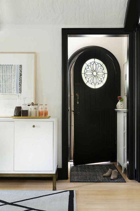 Black plank arch front door with a stained glass panel invites a vintage appeal to the foyer space.