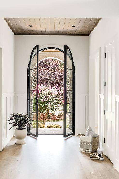 Home entry features steel and glass arch doors.