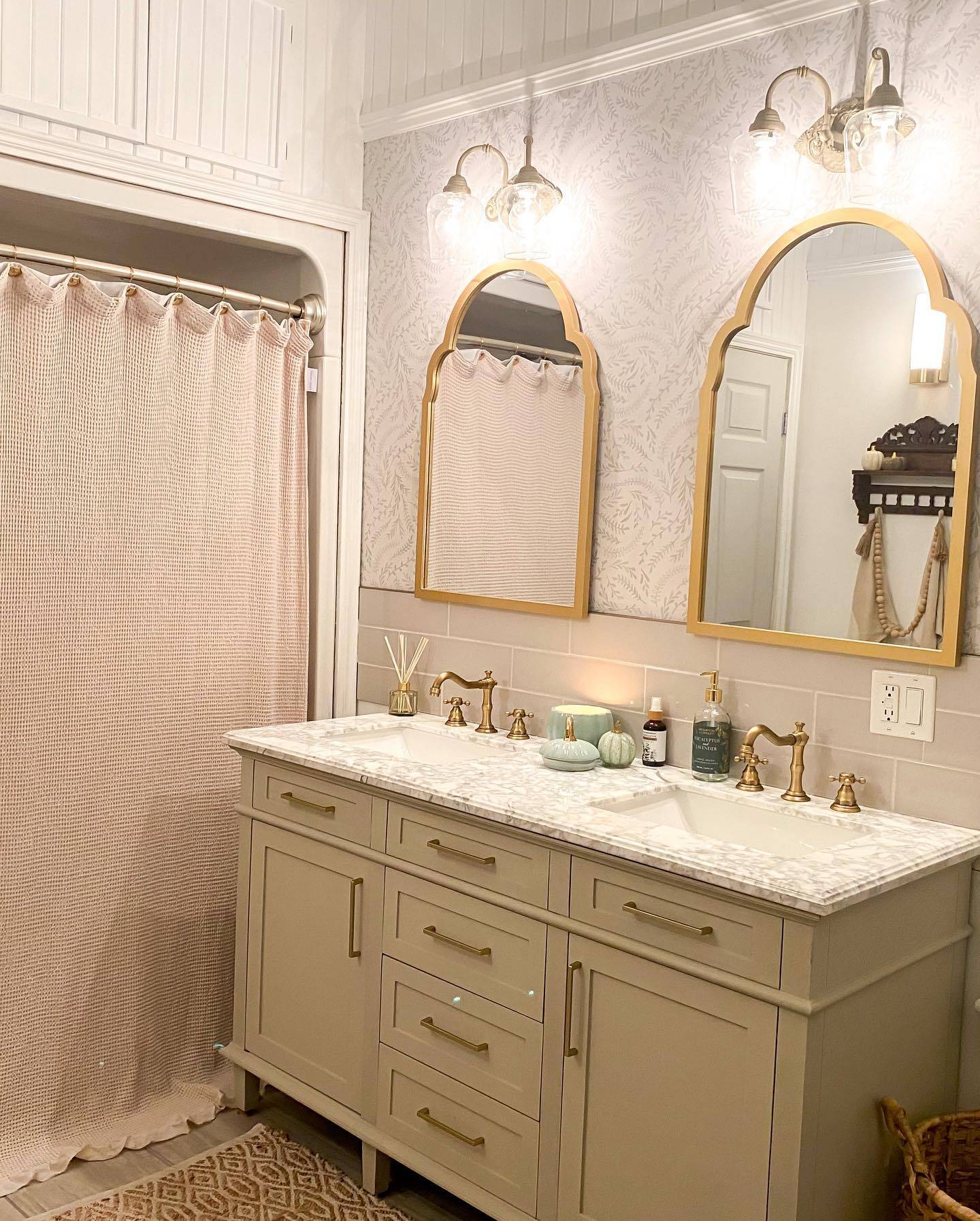 bathroom with two gold arch mirrors vanity and sconces