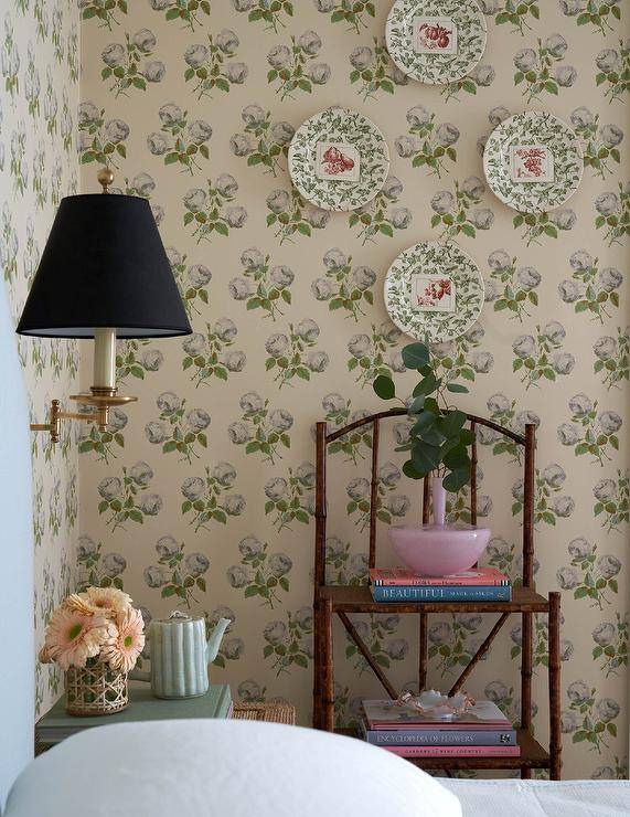 Cottage bedroom with decorative wall plates on a shabby chic floral wallpaper wall.