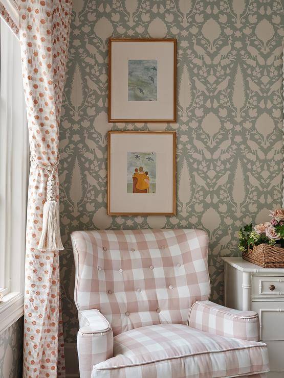 Bedroom features a pink gingham tufted chair with white and pink curtains and a white dresser on Schumacher Chenonceau wallpaper.