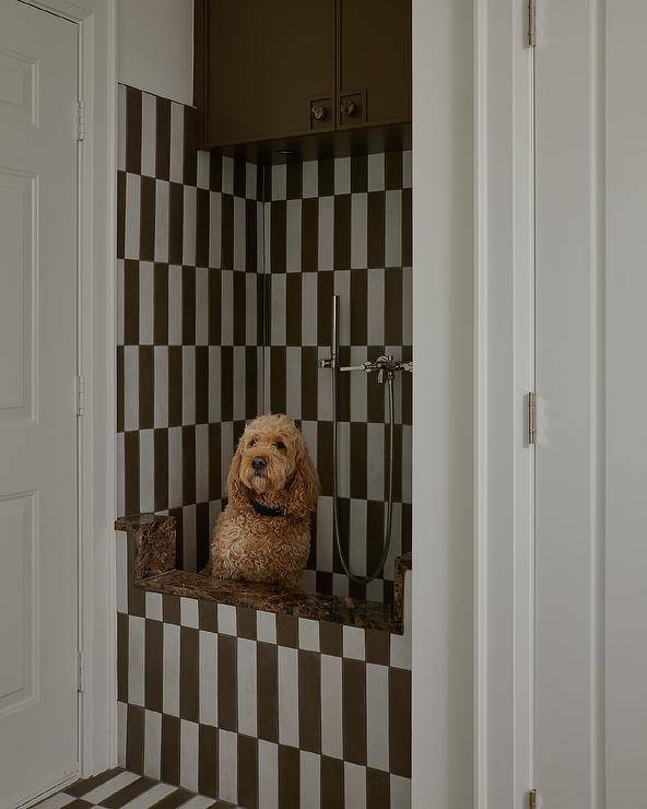 White and brown striped floor tiles lead to a white and brown striped tiled dog shower finished with a polished nickel sprayer mounted to white and brown stripe backsplash tiles.