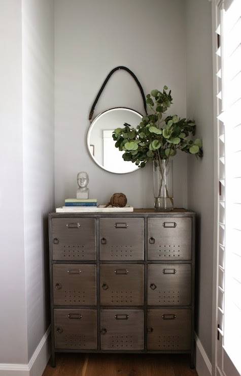 Entryway alcove with walls painted Benjamin Moore Gray Owl framing a Pottery Barn Arden Locker topped with stacked books and a miniature bust alongside a glass vase full of greenery with captains style mirror above.