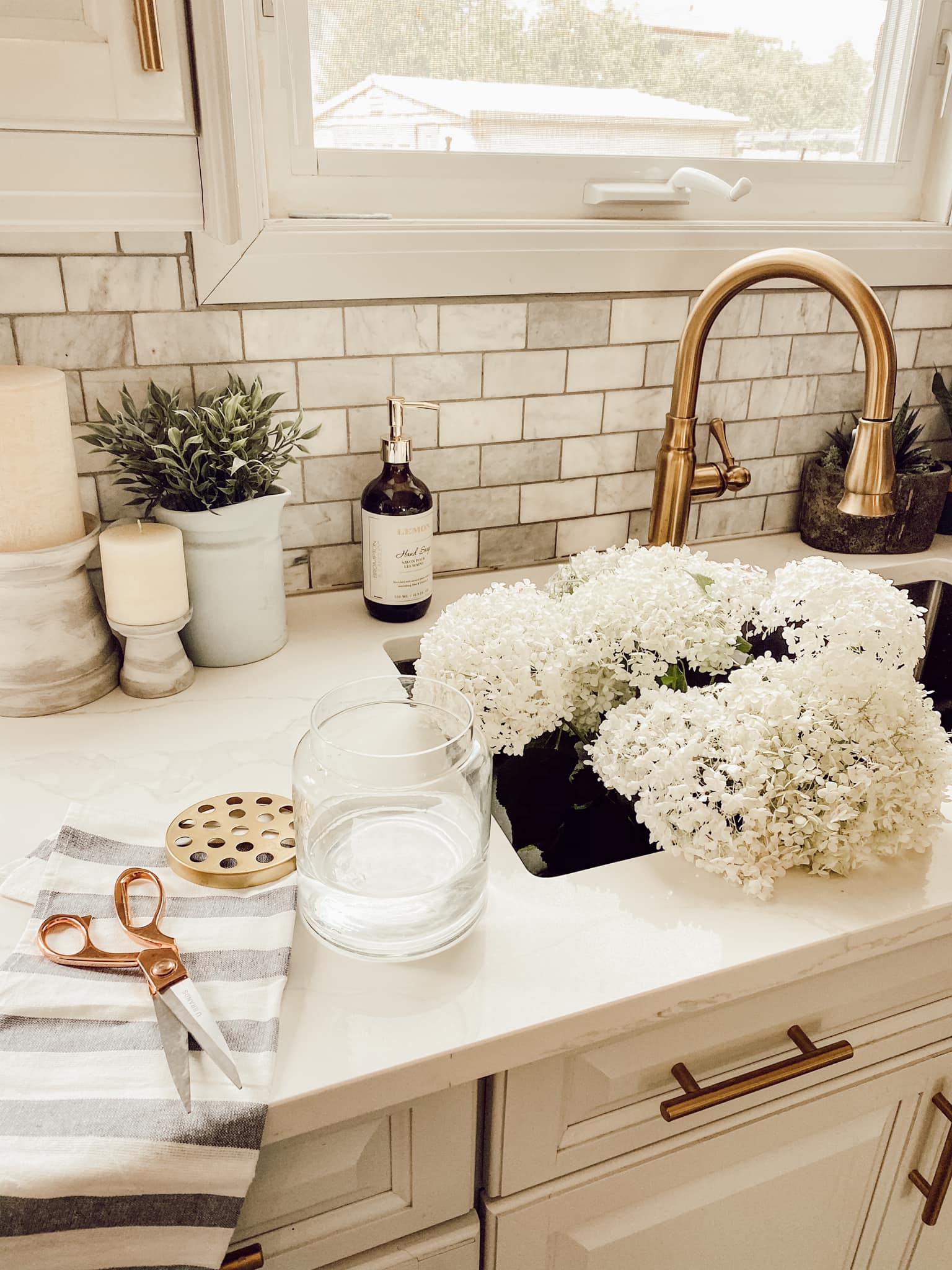 sink filled with white hydrangea gold faucet