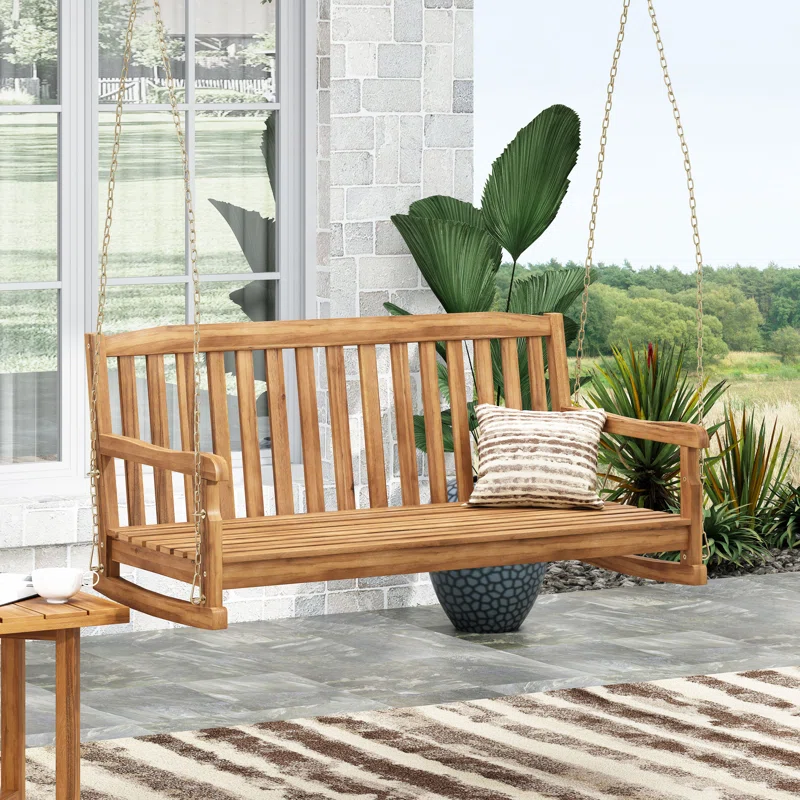 wood porch swing on patio with patio plant in background