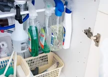 spray bottles hanging from tension rod under kitchen cabinet