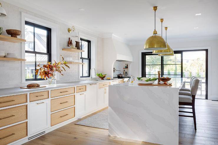 Heather gray counter stools sit at a marble-look waterfall edge top island illuminated by Eugene Pendants.