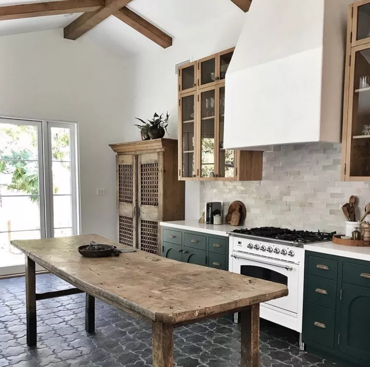 white stove with large range hood green cupboards and rust wood harvest table