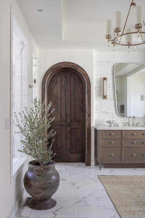 Marble floor tiles lead to brown arch bi-fold bathroom doors.