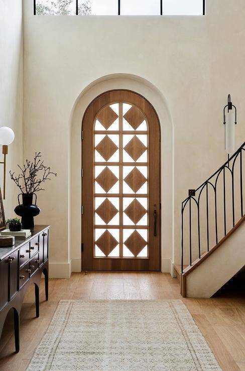 An arched front door is finished with stunning diamond wood panels.