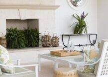 White aluminum lounge chairs with green and white cushions are placed on a beige outdoor rug and matched with beige rope stools in a gorgeous covered patio.