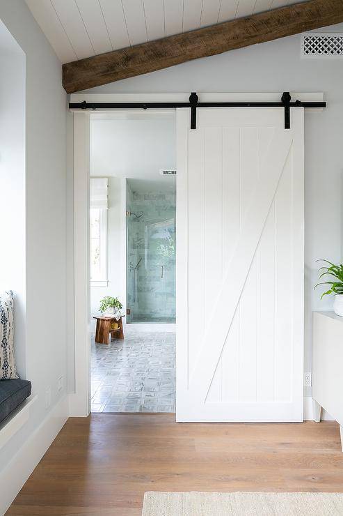 A shiplap barn door on rails slides open to reveal a stunning master bathroom.