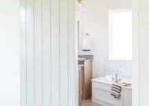 A white plank barn door on rails opens to a bathroom.